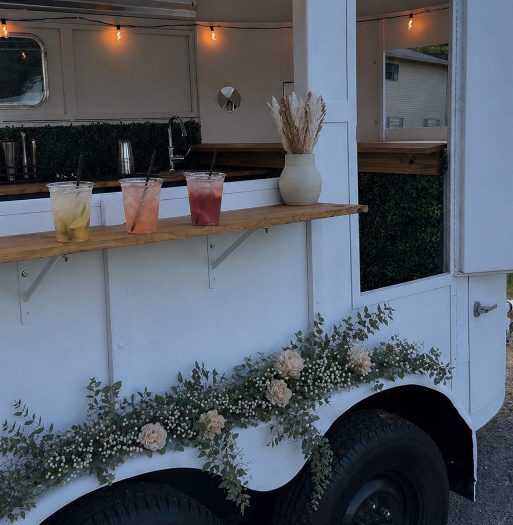 Three drinks lined up along the trailer's wooden bar shelf