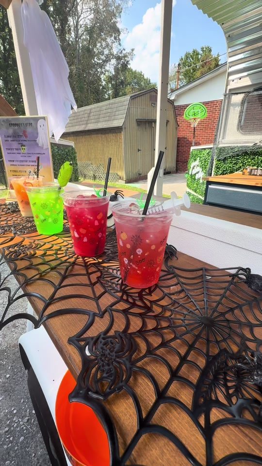 Halloween drinks in printed cups on a spiderweb table runner