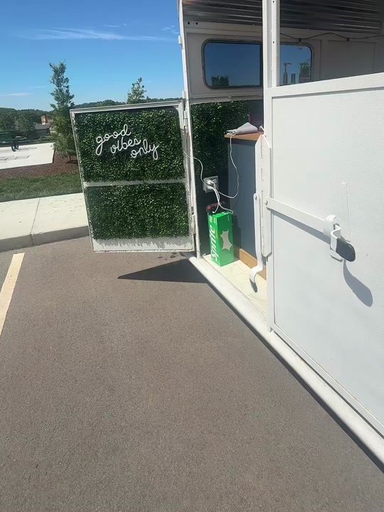 A good vibes only neon sign mounted on a boxwood hedge panel